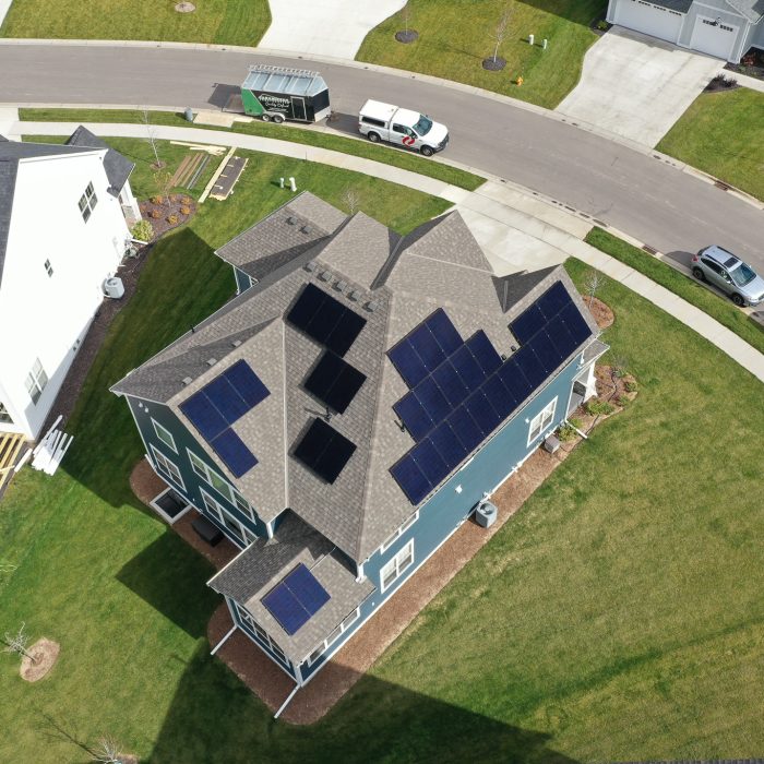 Aerial view of solar panels installed in a field under blue skies - Home Solar Panel Installation