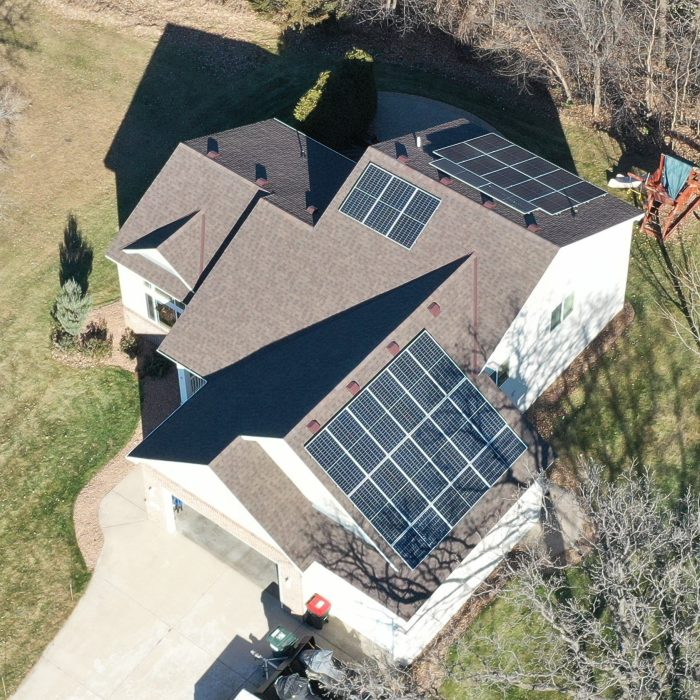 Aerial view of a solar panel installation with rows of solar panels under a clear blue sky - Cedar Creek Energy