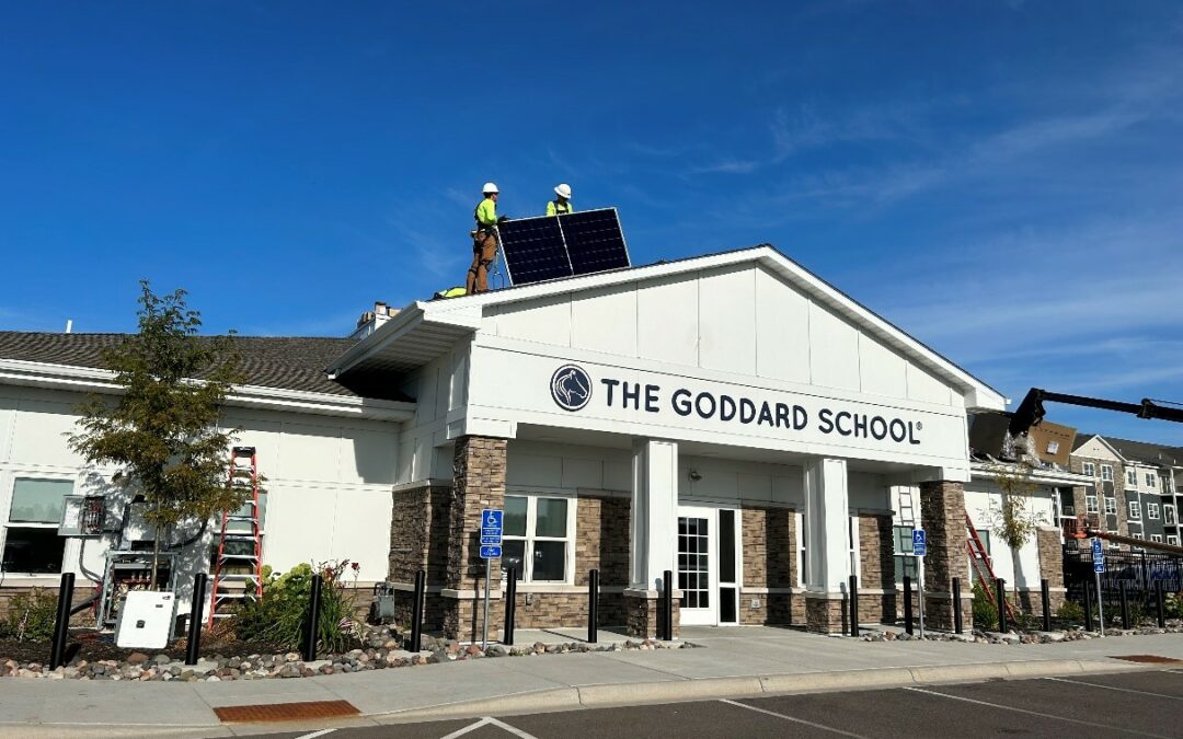 a man standing on top of a roof next to a building - Solar for Schools