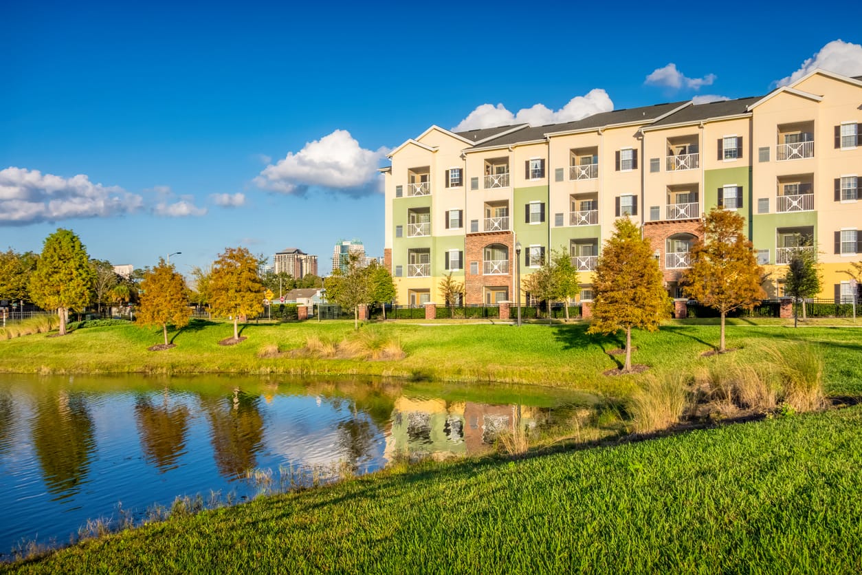 A multifamily housing complex with a pond in front of it, promoting sustainable living - Minnesota Solar Energy Company
