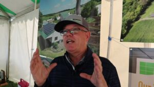 a man standing in front of a picture of a farm - Solar Energy for Farmers and Rural Businesses