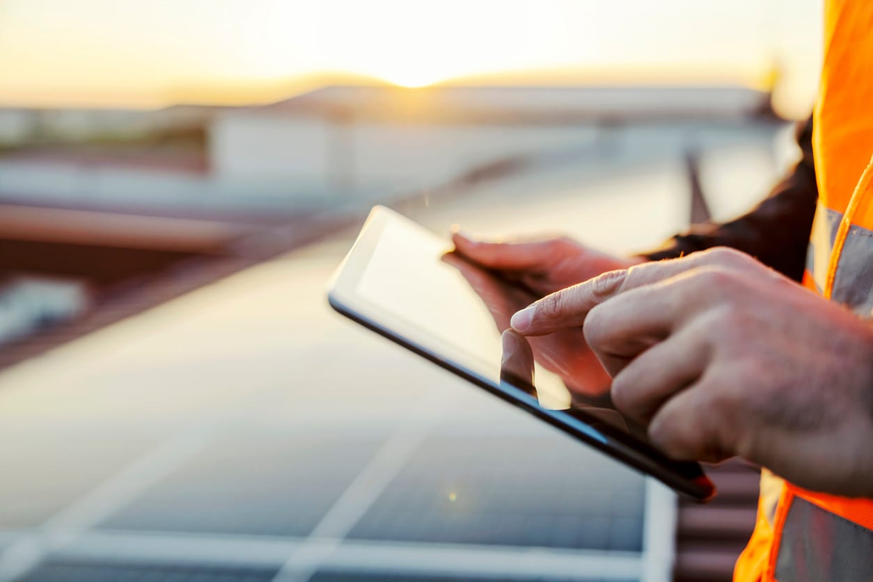 a person holding a tablet on top of a roof - Solar Project Longevity