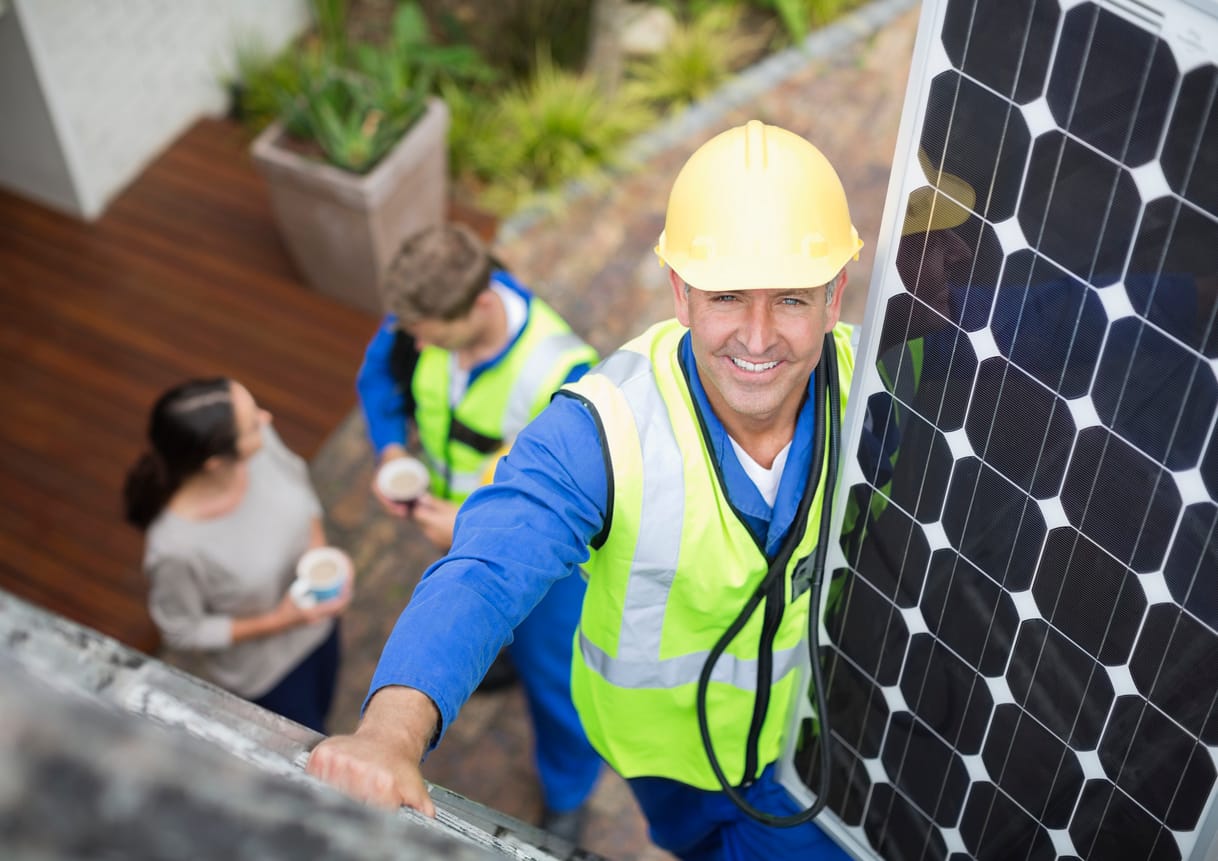 a man standing next to a solar panel - solar panel installation company
