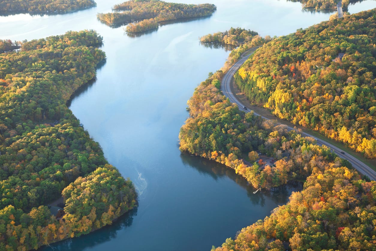 an aerial view of a winding road surrounded by trees - Solar Energy