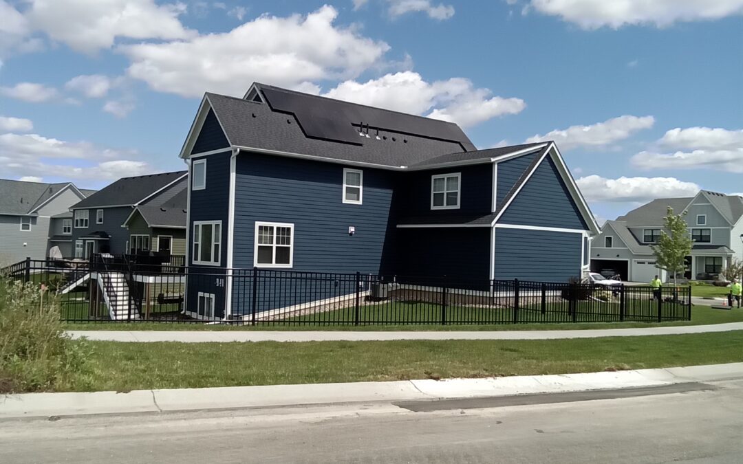 a blue house with a black fence in front of it - Residential Solar in Minnesota